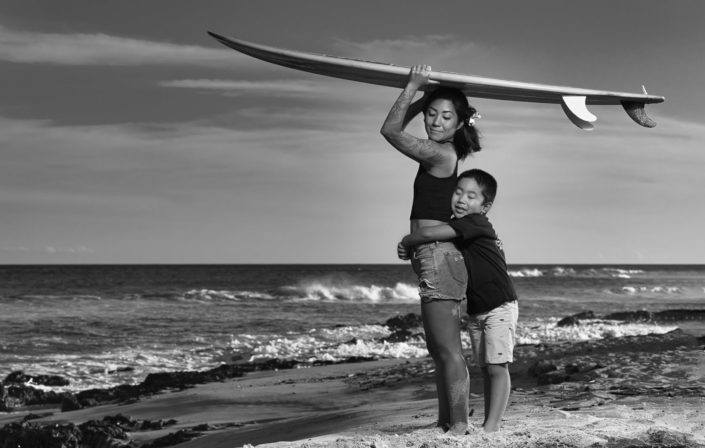 Mom & young son surfer family portrait at sunset.