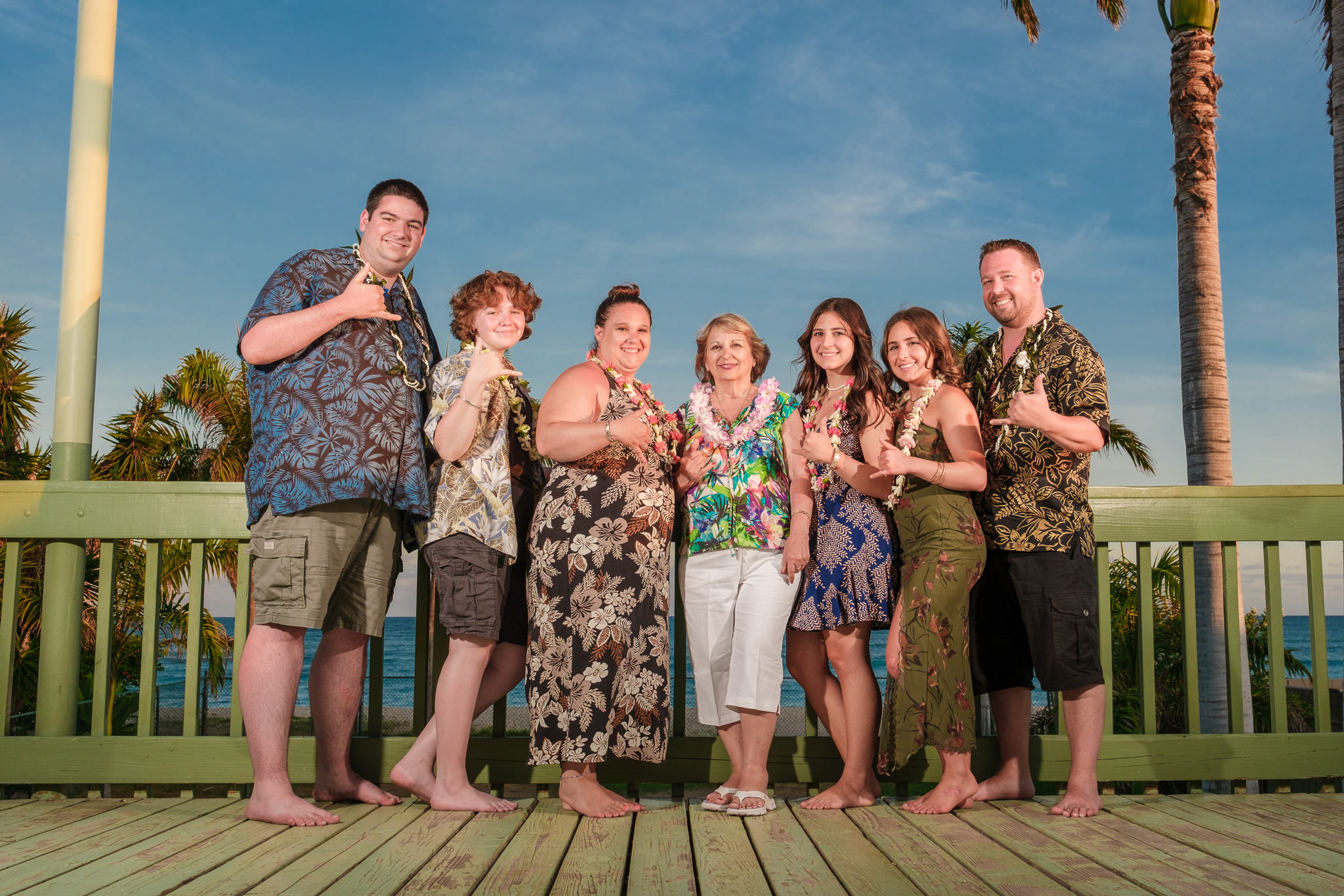 Honolulu Family Ohana Portraits Photography Oahu Photographer A Honolulu photographer captures family ohana portraits on Oahu. A large group poses together in floral attire and leis for professional beach photography.